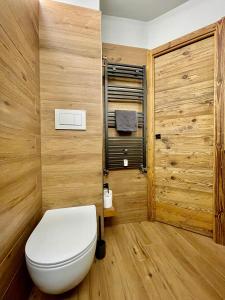 a bathroom with a white toilet and wooden walls at Panoramic Apartment in Breuil-Cervinia