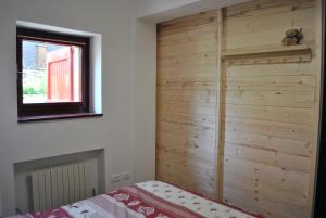 a bedroom with a wooden wall next to a bed at La casetta di Viola in Abetone