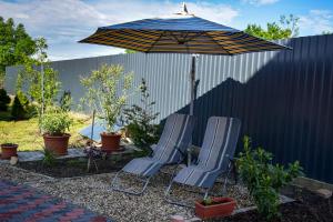 twee stoelen en een paraplu in een tuin bij LUX Apartman Maroslele in Maroslele