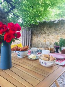 een tafel met een vaas rozen en eten erop bij La maison des secrets in Bédoin