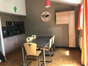 a table and chairs in a kitchen with a clock on the wall at Le repaire des écureuils Vallée de Rabais in Virton