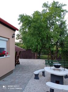 a patio with two benches and a table and a tree at Sárgapart Holiday Home in Poroszló