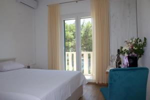 a bedroom with a bed and a window and a blue chair at Apartmani Bauk in Pučišća