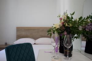 un tavolo con due bicchieri di vino e fiori sopra di Apartmani Bauk a Pučišća