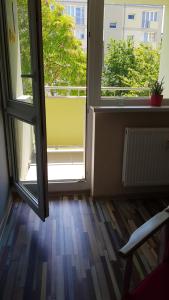 an empty room with two large windows and a wooden floor at Vanilla Apartment in Kołobrzeg