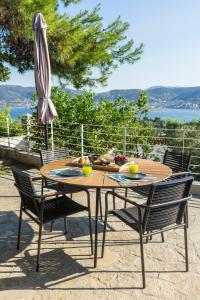 einen Holztisch mit Stühlen und einem Sonnenschirm in der Unterkunft The H Experience - The Blue Lounge with Swimming pool in Porto Rafti