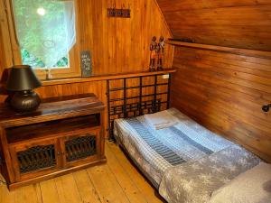 a bedroom with a bed and a wooden wall at Rożnów domek pod Zamkiem in Rożnów