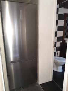 a stainless steel refrigerator in a bathroom with a toilet at B&B Janine in Ostend