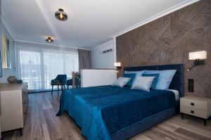 sypialnia z niebieskim łóżkiem i biurkiem w obiekcie ApartPark ALBUS 401 SEA VIEW above the trees w Świnoujściu