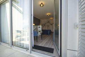 a sliding glass door leading to a room with a table at ApartPark ALBUS 401 SEA VIEW above the trees in Świnoujście