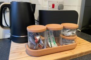 a tray with three jars of utensils on a counter at BOUTIQUE CITY CENTRE APARTMENT WITH PARKING in Chester