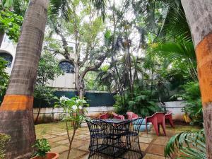 a patio with red chairs and a table and trees at Hostel Lifespace- Twin Bungalow with Pods, Bunks, Private Rooms, CoWork & Cafe in Pune