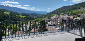 a balcony with a view of a town and mountains at Molaris Lodge in Mühlbach
