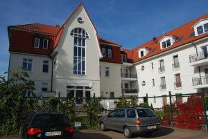 two cars parked in a parking lot in front of a building at Ostseeblick Ferienwohnung in Am Schwarzen Busch