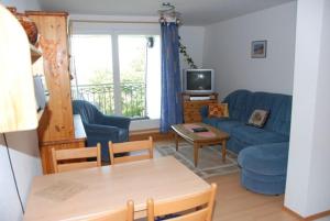 a living room with a blue couch and a table at Ostseeblick Ferienwohnung in Am Schwarzen Busch