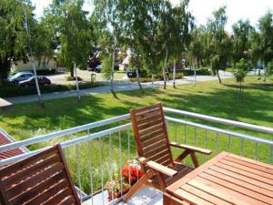 two wooden chairs and a table on a balcony at Sonnendeck in Kaltenhof