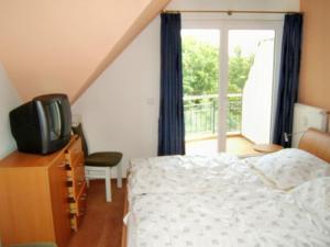 a bedroom with a bed and a television and a balcony at Seesternchen in Am Schwarzen Busch