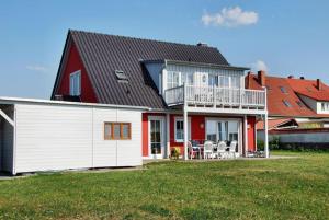 a red and white house with a deck and a balcony at "Utkiek" im "Roden Hus" in Timmendorf