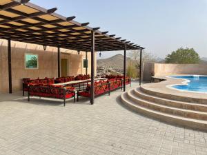 a pavilion with red chairs and a swimming pool at Alshahad farmhouse in Fujairah