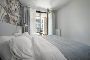 biała sypialnia z łóżkiem z białymi poduszkami w obiekcie Apartament Pastelowa Portova w mieście Gdynia