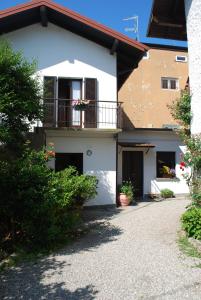 a white house with a balcony and a driveway at La casetta del nonno Giampi in Sesto Calende