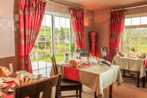 un comedor con mesas y ventanas con cortinas rojas en Sea Villa, en Ardgroom
