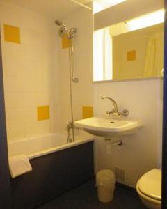 La salle de bains est pourvue d'un lavabo, de toilettes et d'une baignoire. dans l'établissement Hotel Amys Voreppe, à Voreppe