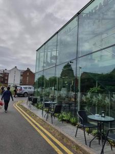 a person walking past a glass building with tables and chairs at The Old Mill Thai vintage in Whitchurch