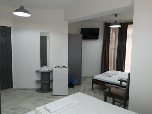 Cette chambre blanche dispose d'une table, d'un lavabo, d'une table et de chaises. dans l'établissement Casa George Mamaia Nord, à Mamaia Nord – Năvodari