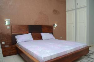 a bed with a wooden headboard in a bedroom at Hotel La Perle in Saint-Louis