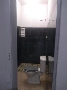 a bathroom with a toilet and a black tiled wall at Hostel Viajante Marajo in Soure