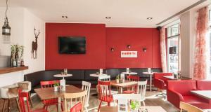 a restaurant with red walls and tables and chairs at Sure Hotel by Best Western Muenchen Hauptbahnhof in Munich
