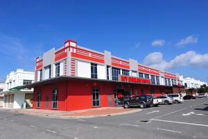 un edificio rojo y blanco con coches estacionados en un estacionamiento en My Dream Hotel, en Kampong Ayer