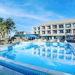 a large swimming pool in front of a hotel at Dammora Resort in Seogwipo