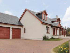 een wit huis met rode deuren en een oprit bij 3 Croftside in Aviemore