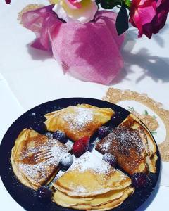 a plate of pancakes and berries on a table with flowers at Vila Reni & Risi in Ksamil