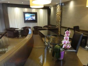 a lobby with couches and tables and a television at Hotel Le Croiseur Intra Muros in Saint Malo