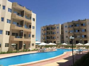 a swimming pool in front of a apartment building at Tahiti North cost تاهيتي الساحل الشمالي in Al Ḩammām