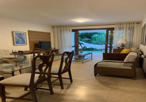 a living room with a couch and a table and chairs at Apartamento Reserva Imbassai - Terraco Buganvilias in Imbassai