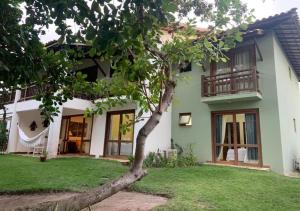 a house with a tree in front of it at Apartamento Reserva Imbassai - Terraco Buganvilias in Imbassai