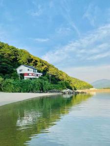a house on a hill next to a body of water at Rakusansui Villa in Itoshima