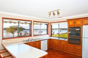 a kitchen with wooden cabinets and windows with a view of the water at HAIS18G - Riverside Delight in Greenwell Point