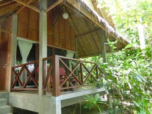 a house with a wooden porch and a balcony at The Narima - SHA Plus in Ko Lanta