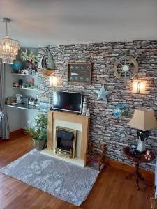 ein Wohnzimmer mit einer Ziegelwand und einem Kamin in der Unterkunft A New U Country Cottage in Valentia Island