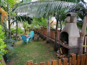 a patio with a fireplace and chairs and palm trees at Chez Nadine & Patrick in Saint-Paul