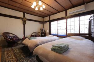 a bedroom with two beds in a room with windows at Shanti House Sakaiminato in Sakaiminato