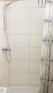 zasłonę prysznicową w łazience wyłożonej białymi kafelkami w obiekcie Fewo am Museum w mieście Schifferstadt