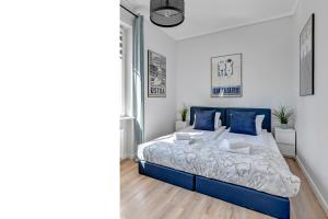 a bedroom with a large bed with blue pillows at Lion Apartments - Ibiza in Sopot
