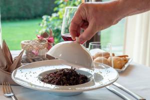 a person is reaching for a plate of food at Draconerium Hotel in Dronero