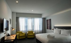 um quarto de hotel com uma cama e duas cadeiras amarelas em The Gerald Apartment Hotel em Geraldton